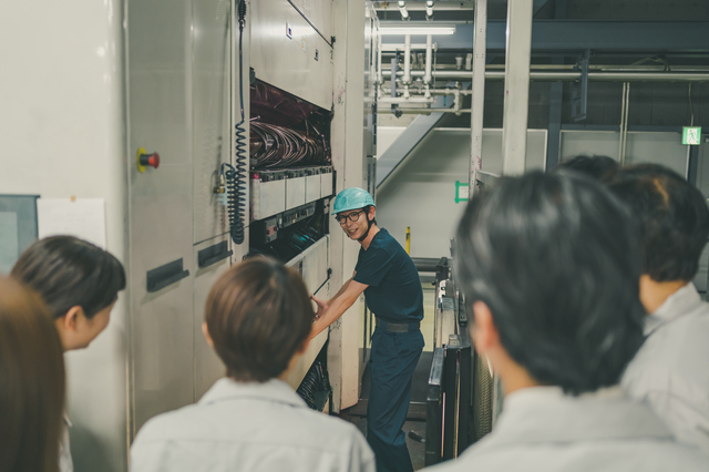 工場見学の案内をするスタッフと参加者