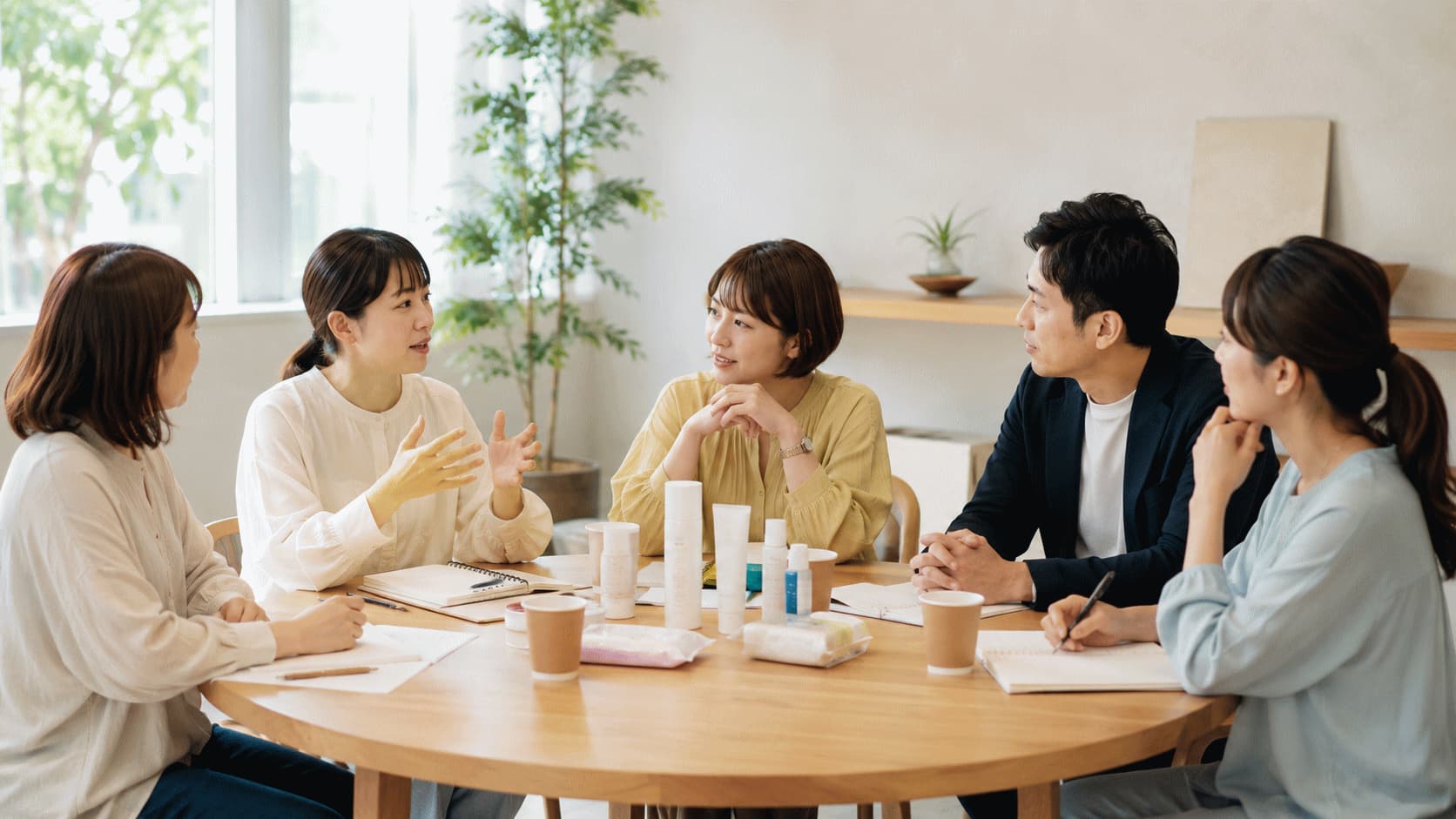 企業担当者と4人の生活者が丸テーブルを囲み、商品を前に意見を交わしている共創セッションの様子